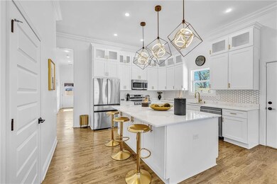 Kitchen featuring stainless steel appliances, a kitchen bar, white cabinetry, light countertops, and a kitchen island