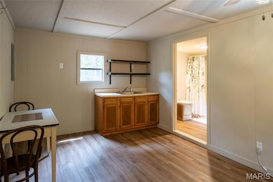 Kitchen with brown cabinets, light wood finished floors, open shelves, light countertops, and a decorative wall