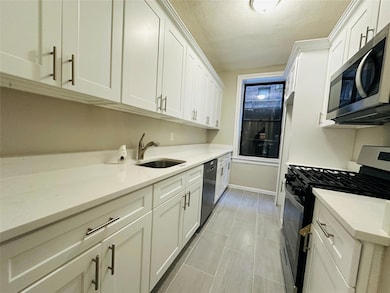 Kitchen with white cabinetry, sink, stainless steel appliances, and a textured ceiling