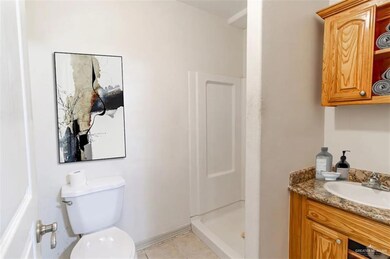 Bathroom with toilet, a shower, tile patterned flooring, and vanity