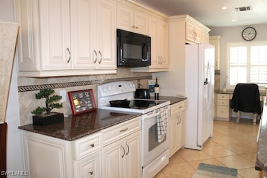 Kitchen with tasteful backsplash, visible vents, white appliances, and light tile patterned floors