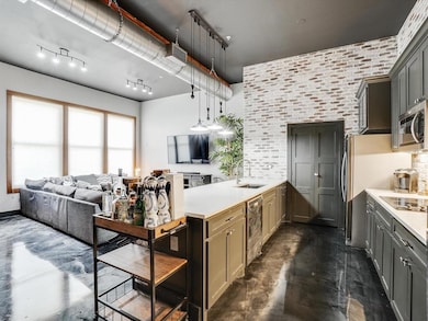 Kitchen featuring sink, rail lighting, brick wall,