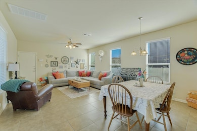 Dining space featuring light tile patterned floors, ceiling fan, and open to the main living area