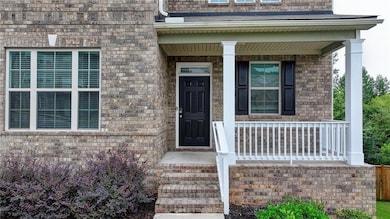 View of exterior entry with a porch and brick siding
