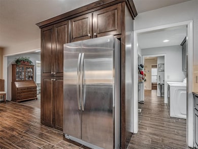 Kitchen featuring freestanding refrigerator, dark wood finished floors, dark brown cabinets, and washer / clothes dryer