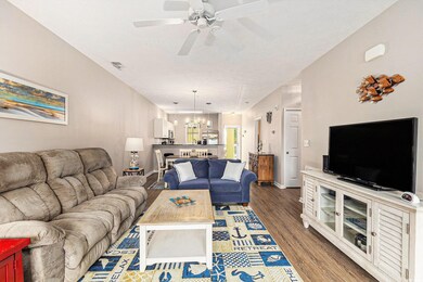 Living area featuring a chandelier, wood finished floors, a ceiling fan, and baseboards