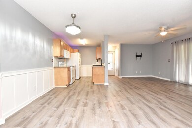 Kitchen featuring open floor plan, white stove, ceiling fan, light wood finished floors, and wainscoting