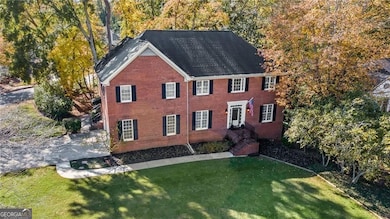 Colonial house featuring a front yard, brick siding, and a shingled roof