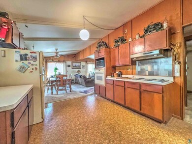 Kitchen with white appliances, ceiling fan, brown cabinetry, light countertops, and under cabinet range hood