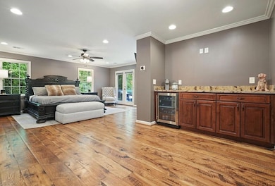 Upstairs Primary suite featuring french doors giving access to large balcony with lake view, reclaimed hickory milled hardwood floors, spacious coffee bar, recessed lighting