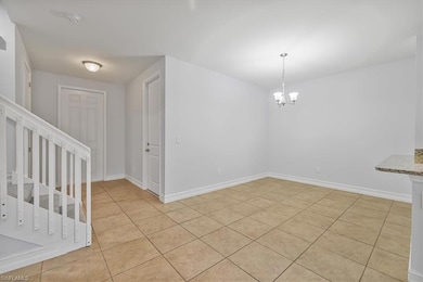 Unfurnished dining area featuring a chandelier, light tile patterned floors, baseboards, and stairway