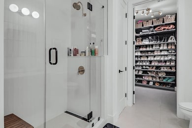 Bathroom with a shower stall, tile patterned floors, and a closet