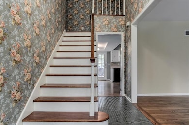 Staircase featuring wallpapered walls and wood finished floors