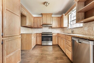 Kitchen featuring appliances with stainless steel finishes, light brown cabinets, wood finished floors, and a sink