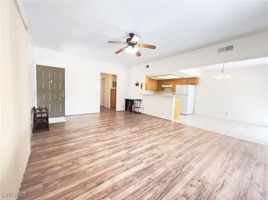 Unfurnished living room featuring light wood-style flooring, ceiling fan, and a chandelier