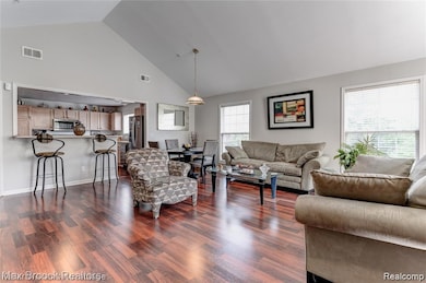 Living room with high vaulted ceiling and dark wood-type flooring