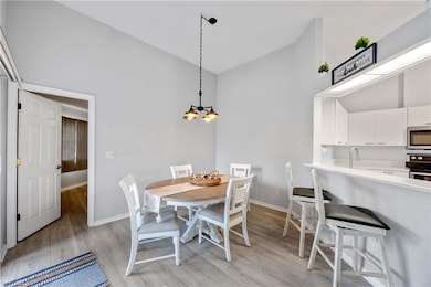 Dining room with a chandelier, sink, high vaulted ceiling, and light hardwood / wood-style flooring