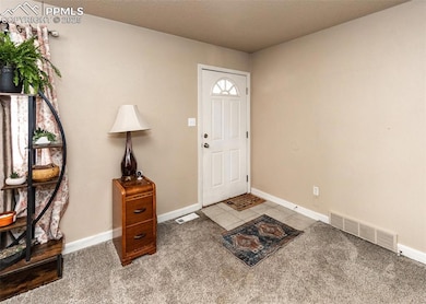 Foyer featuring baseboards, light colored carpet, 