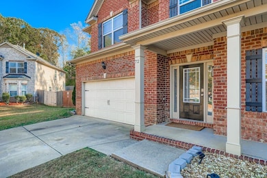 Doorway to property featuring a porch, brick siding, an attached garage, and concrete driveway