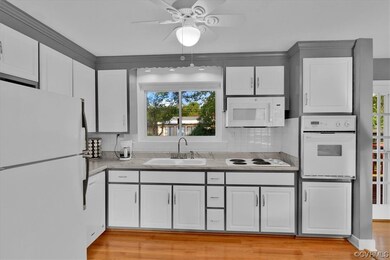 Kitchen featuring white cabinetry, white appliances, backsplash, light hardwood floors, and ceiling fan