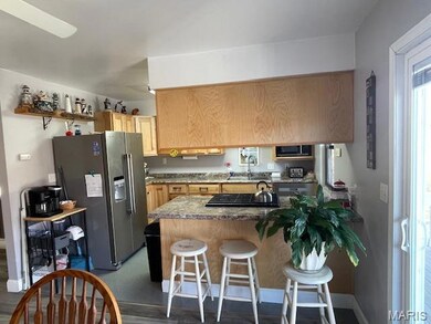 Kitchen with black appliances, a breakfast bar, dark wood-style floors, a peninsula, and light brown cabinetry