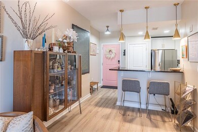 Kitchen with freestanding refrigerator, light wood-style flooring, a breakfast bar, white cabinetry, and hanging light fixtures