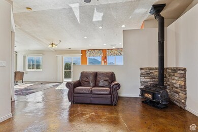 Living area with a wood stove, plenty of natural light, a textured ceiling, finished concrete flooring, and recessed lighting