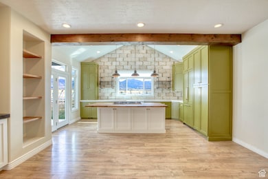Kitchen featuring open shelves, green cabinets, backsplash, built in features, and light wood-style flooring
