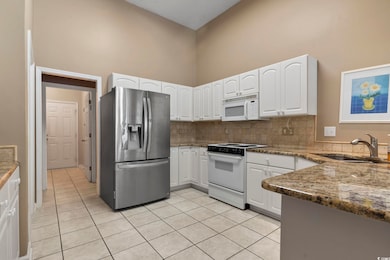 Kitchen with white cabinets, dark stone counters, 
