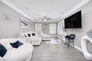 Living area featuring ornamental molding, wood finished floors, and a ceiling fan