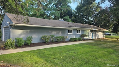 Ranch-style house featuring a front lawn, a garage, a shingled roof, brick siding, and a chimney