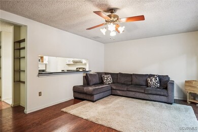 Living room featuring ceiling fan, wood finished floors, and a textured ceiling