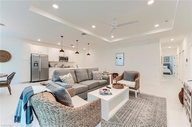Living room with a raised ceiling, recessed lighting, a ceiling fan, and light tile patterned flooring