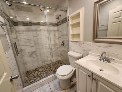 Bathroom with vanity, a shower stall, tile walls, and light tile patterned floors