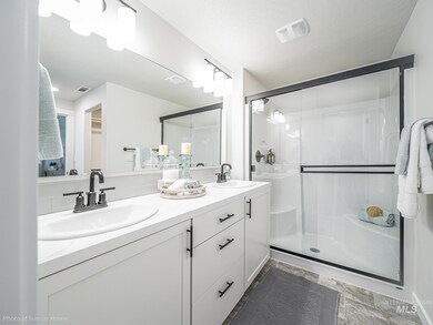 Full bath with a stall shower, double vanity, and tasteful backsplash