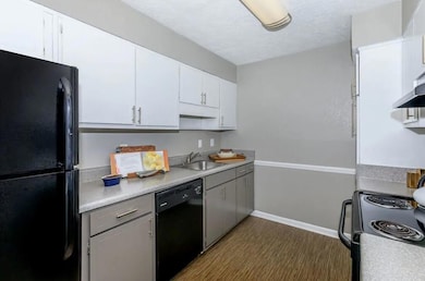 Kitchen with black appliances, wood-type flooring,
