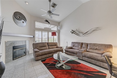 Living area with a ceiling fan, a tile fireplace,