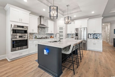 Kitchen with white cabinets, a tray ceiling, decorative backsplash, ornamental molding, and a kitchen bar