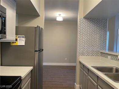 Kitchen featuring tasteful backsplash, dark wood finished floors, stainless steel microwave, and light stone countertops