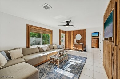 Tiled living room with ceiling fan and wood walls