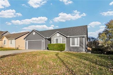 Single story home featuring driveway, a front lawn, a garage, stone siding, and roof with shingles