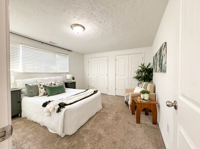 Bedroom featuring light carpet, multiple closets, and a textured ceiling