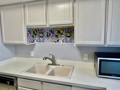 Kitchen with light countertops, appliances with stainless steel finishes, and white cabinets