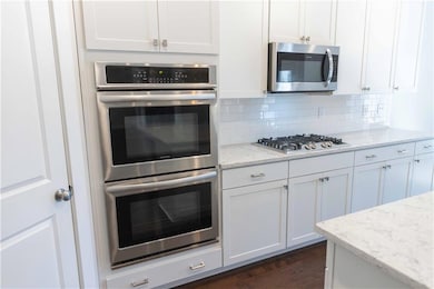 Kitchen featuring light stone counters, white cabi
