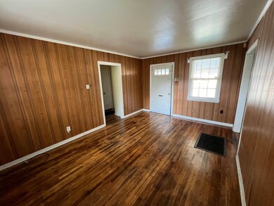 Foyer with crown molding, wood walls, and dark har