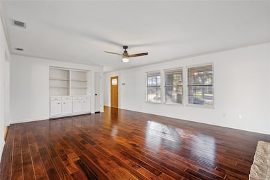 Unfurnished living room with ornamental molding, a ceiling fan, dark wood-type flooring, and built in features