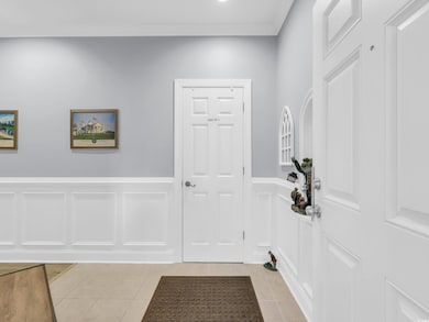 Entryway featuring tile patterned floors, a decorative wall, and a wainscoted wall