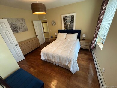 Bedroom featuring a baseboard heating unit and dark wood-type flooring