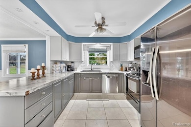 Kitchen featuring black appliances, gray cabinetry, tasteful backsplash, ornamental molding, and light countertops