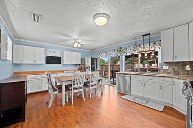 Kitchen with ceiling fan, white cabinetry, and lig